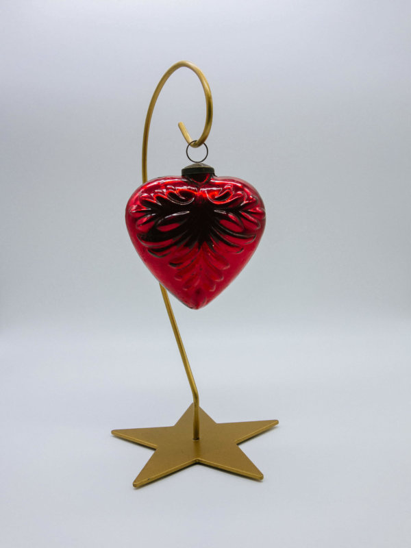 Rotes Herz mit Ornamenten ab einem Ständer aufgehängt