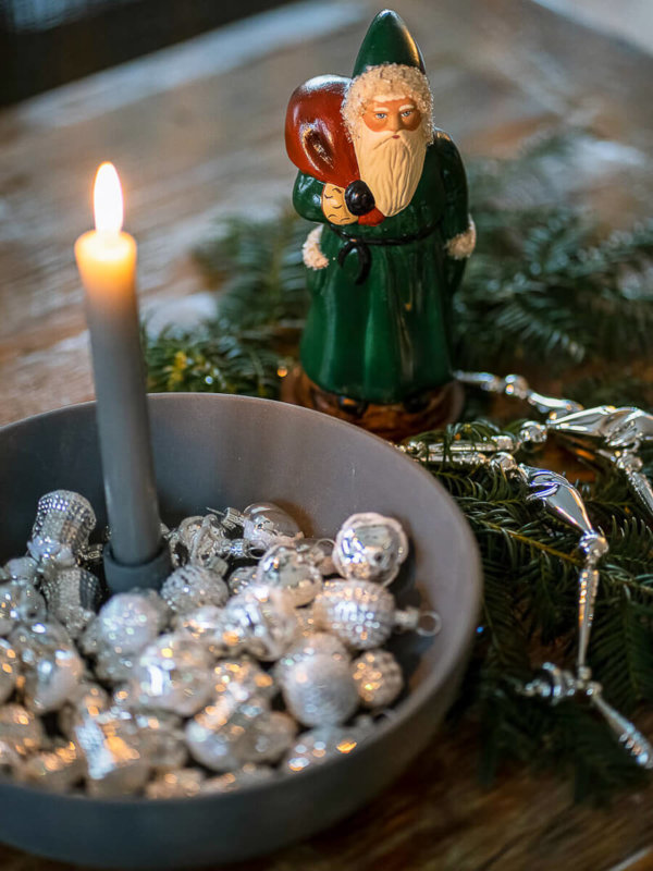 Mini Christbaumornamente in einer Schale mit Kerze und einem Nikolaus