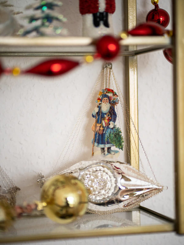Weihnachtsmann im Schiff in einem Regal mit anderem Christbaumschmuck